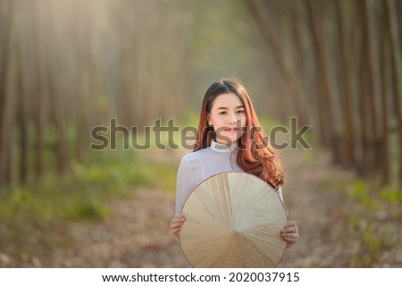 Asian woman Vietnam culture traditional dress in rubber forest during sunset,vintage style