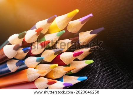 New color sharpened pencils on a dark background with sunlight or illumination. Abstract background on a creative theme. Back to school.