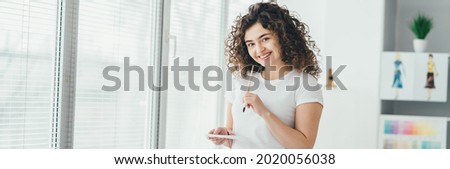 The curly girl with a brush drawing pictures on the table