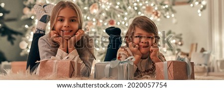 The happy boy and girl with gifts laying on a floor