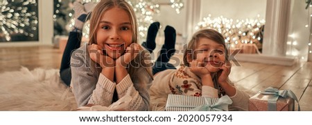 The happy girl and boy with gifts laying on the floor