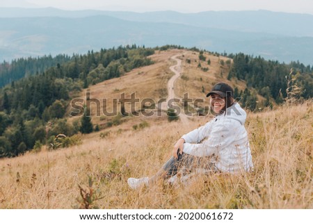 woman sitting on the ground looking at mountains hiking concept autumn season