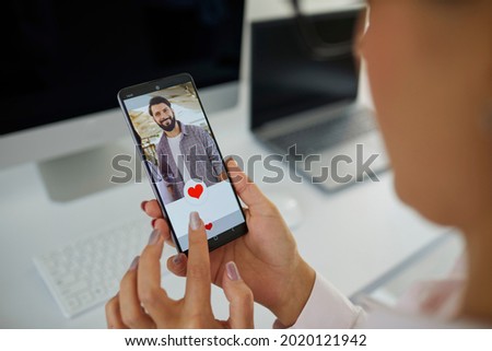 Bringing together people of different professions and walks of life through online dating apps or websites. Close up businesswoman looking at phone display gives like to photo of handsome young farmer