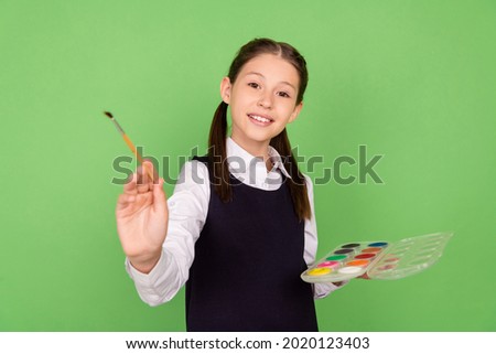Photo portrait schoolgirl creating image with palette with paint brush on art lesson isolated pastel green color background