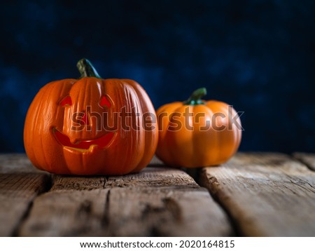 Mysterious mystical holiday Halloween. The symbol of the holiday is two orange pumpkins on a wooden table against the background of a dark night sky. There is a place for an inscription.