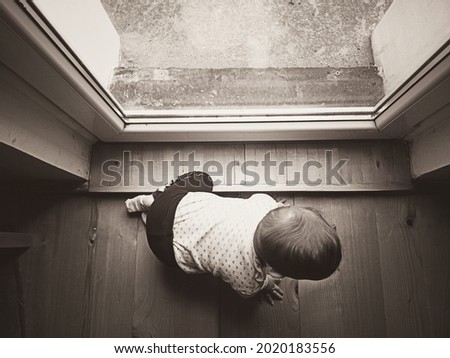 One year baby crawling on the floor beside the terrace door of the house Sepia photo of a baby from above perspective