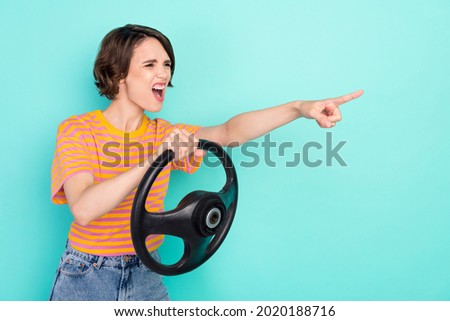 Photo of angry crazy lady wear orange t-shirt holding steering wheel pointing finger empty space isolated turquoise color background