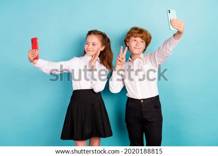 Portrait of two attractive friends friendship taking selfie showing v-sign isolated over bright blue color background