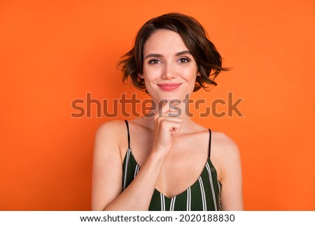 Photo of young girl hand touch chin happy positive smile think thoughtful isolated over orange color background