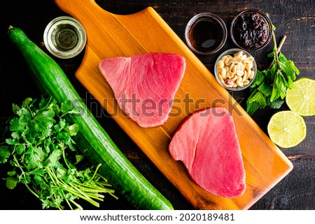Raw Ingredients for Tuna Steaks with Cucumber-Peanut Salad: Uncooked tuna steaks, cucumber, and other recipe ingredients