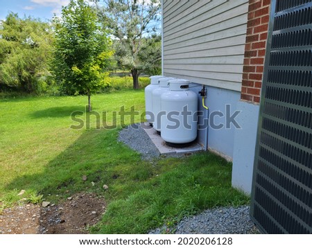 Three propane tanks on the outside of a home. Royalty-Free Stock Photo #2020206128