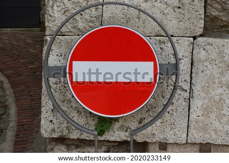 One red no entry traffic sign  . The  sign is hanging  on a metal base