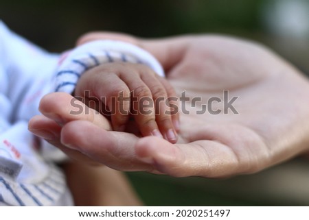 mother's hand holding the baby's hand in white clothes. the concept of mother's love. Baby new born.