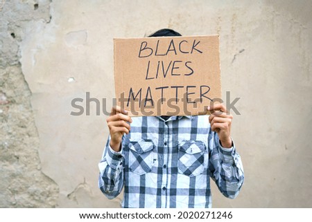 A man holds a cardboard with an inscription, black life has
