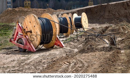 Cable high voltage electric in roll or round coil on ground. Concept of electricity supply for construction projects. Several wooden coils with power cable laid in trench 16x9 image. Royalty-Free Stock Photo #2020275488