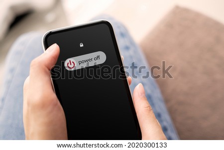 Woman hand using is sliding to turn off the mobile phone to reduce power consumption. Technology and environment concept  Royalty-Free Stock Photo #2020300133