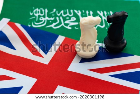 Two knights standing on UK flag and Saudi Arabia flag.