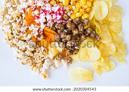 Salty and sweet popcorn and chips on the white background, low angle view