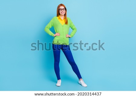 Full size photo of agent young lady wear green sweater trousers sneakers isolated on blue color background