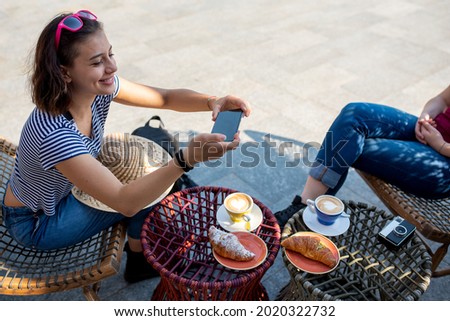 Young woman on holiday photographing breakfast at the bar, table with cappuccino and heart shape on the foam, croissants and vintage camera
, life as travelers and city exploration