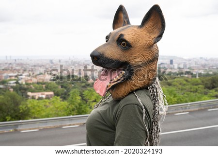 Woman with a latex dog mask, is watching the city from the road
