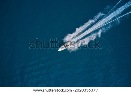 Speed boat faster movement on the water top view. Speedboat wave speed water. Speedboat movement on the water. Speedboat on dark blue water aerial view. Royalty-Free Stock Photo #2020336379