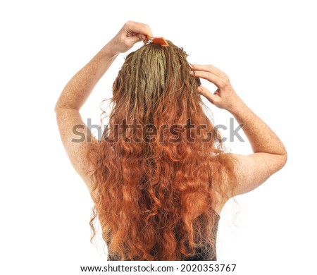 Young woman using henna hair dye on white background