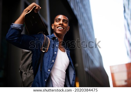 Portrait of happy african-american man with skateboard. Young handsome man with skateboard outdoors.