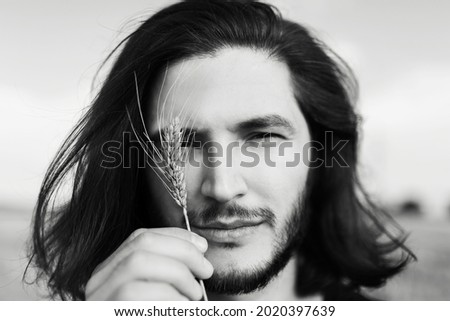 Close-up black and white photo of handsome young man with long dark hair.