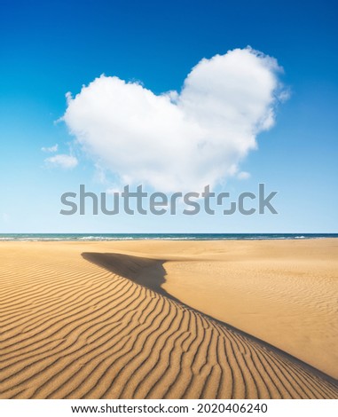 Sand dunes in the desert. Landscape in the daytime. A cloud in the shape of a heart. A blue sky and a heart sign. Lines in the sand. Dunes and sky. 