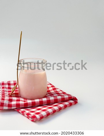 Homemade peach silky pudding in glass jar served with red plaid napkin on white table. selective focus