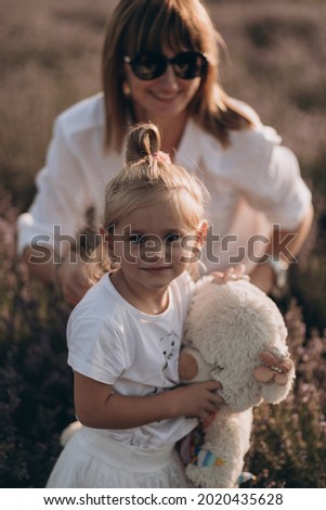 Mother and baby girl walking in lavander field, hugging and having fun outdoor in nature