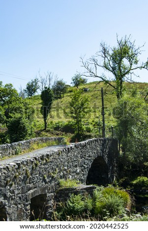 Old stone bridge, over the Dwyfor river, Snowdonia, Wales. Simple, historic structure. Arched design. Rural landscape.  Vertical shot.  Blue sky and copy space. Royalty-Free Stock Photo #2020442525