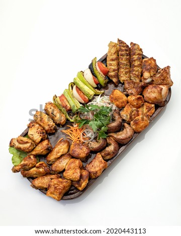 Big set of grilled meat and vegetables. Mixed food on large platter isolated on white background. Top view. Vertical format.