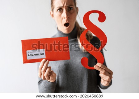 Abmahnung (German for: final notice) Woman Holding and showing a Receiving a Final Notice Envelope and red Paragraph sign. concept of lawyer or business
