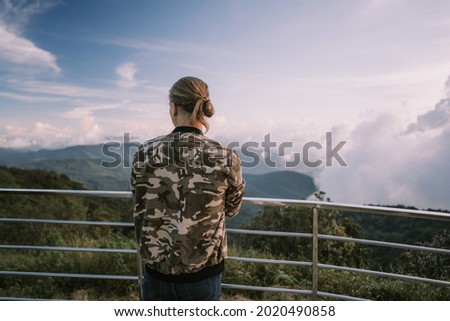 Man photographer in a camouflage jacket shooting sunset with telephoto lens at the highest point in Thailand Doi Ithanon