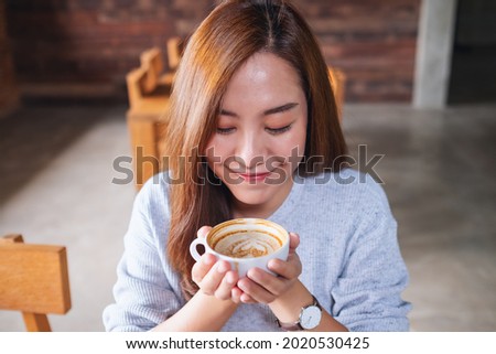 Portrait image of a young asian woman smelling and drinking hot coffee