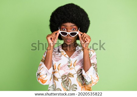 Photo of shocked funky cute girl take off sunglass wear floral print shirt isolated on green color background