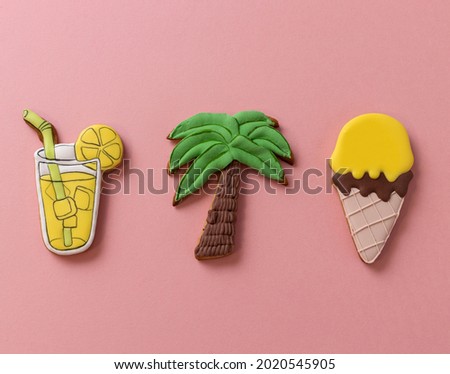 Gang of three summer theme cookies that tempt your senses, palm tree, ice cream and lemonade icing decoration on top, pinkish background concept 