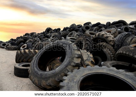 Landfill with old tires and tyres for recycling. Reuse of the waste rubber tyres. Disposal of waste tires. Worn out wheels for recycling. Tyre dump burning plant. Regenerated tire rubber produced.  Royalty-Free Stock Photo #2020571027