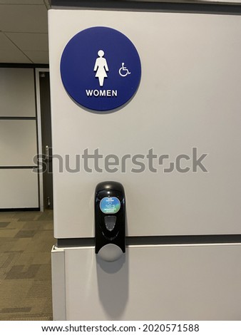 A female bathroom sign and a sanitizer dispenser