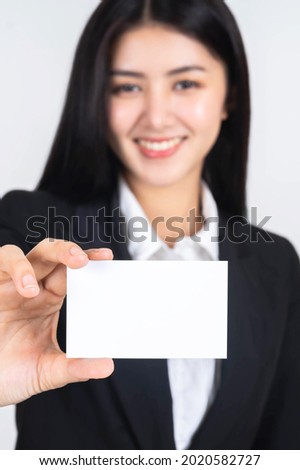 business Asian woman in black suit holding and showing empty blank business card or blank name card - business concept