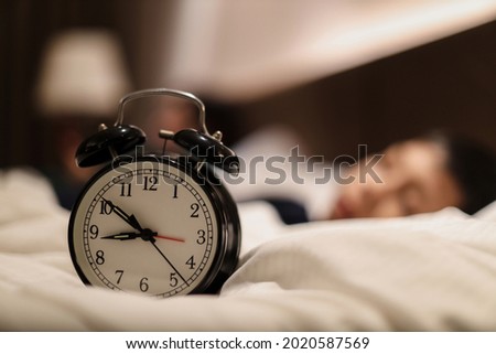 Alarm clock showing 9 o'clock pm with blurry background of boy sleeping on the bed Royalty-Free Stock Photo #2020587569