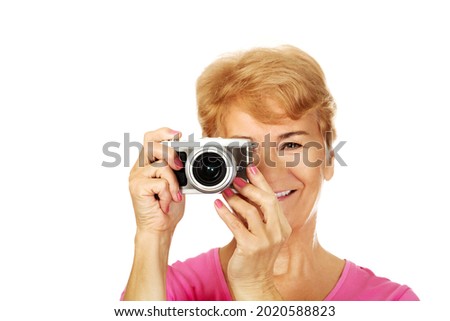 A portrait of an old Polish woman taking a photo with her vintage camera, isolated on white