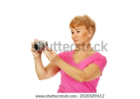 A portrait of an old Polish woman taking a photo with her vintage camera isolated on white