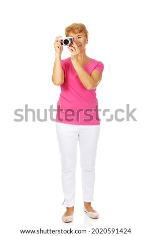 A full body shot of an old Polish woman taking a photo with her vintage camera isolated on white