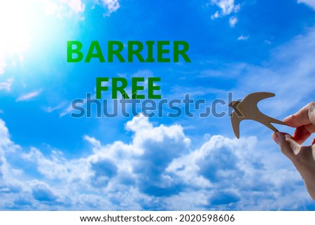 Barrier free symbol. Businessman hand holding wooden bird on cloud blue sky background. Words 'Barrier free'. Sunshine. Business, diversity, inclusion, belonging and barrier free concept. Copy space.