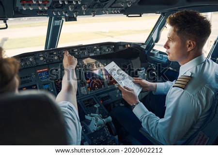 Airline captain and first officer sitting in the cockpit Royalty-Free Stock Photo #2020602212