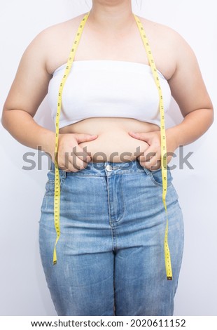 Beautiful fat woman with tape measure She uses her hand to squeeze the excess fat that is isolated on a white background. She wants to lose weight, the concept of surgery and break down fat under the Royalty-Free Stock Photo #2020611152