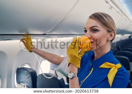 Experienced air hostess using a breathing apparatus in the cabin Royalty-Free Stock Photo #2020613738